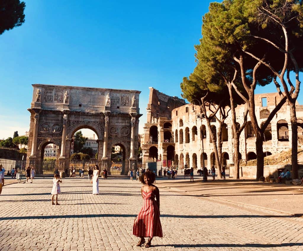 Woman standing in Rome near the Colosseum and Arch of Constantine.
